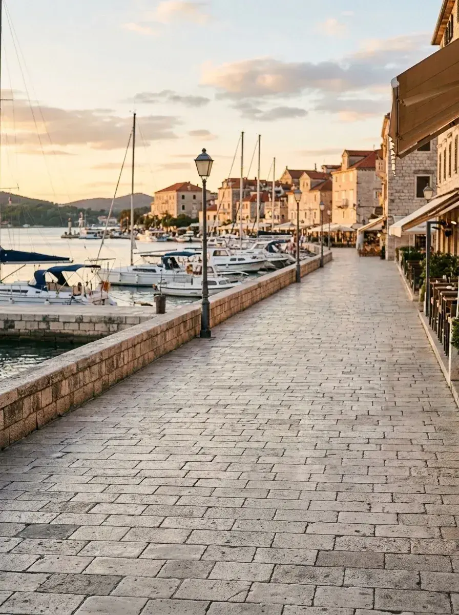 The same stone promenade and harbor scene with all people removed, leaving the walkway empty.