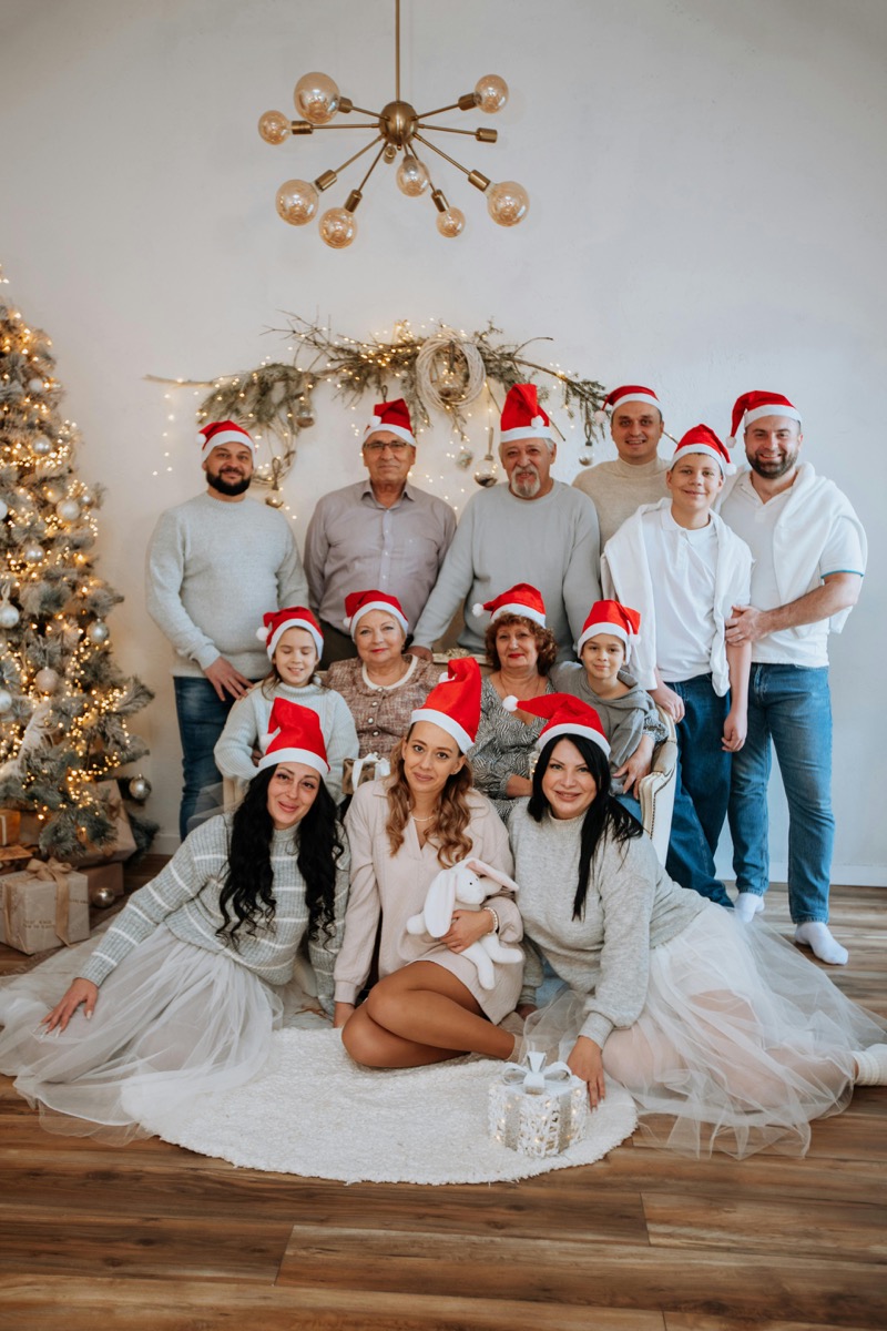 Large family Christmas photo with Santa hats by tree