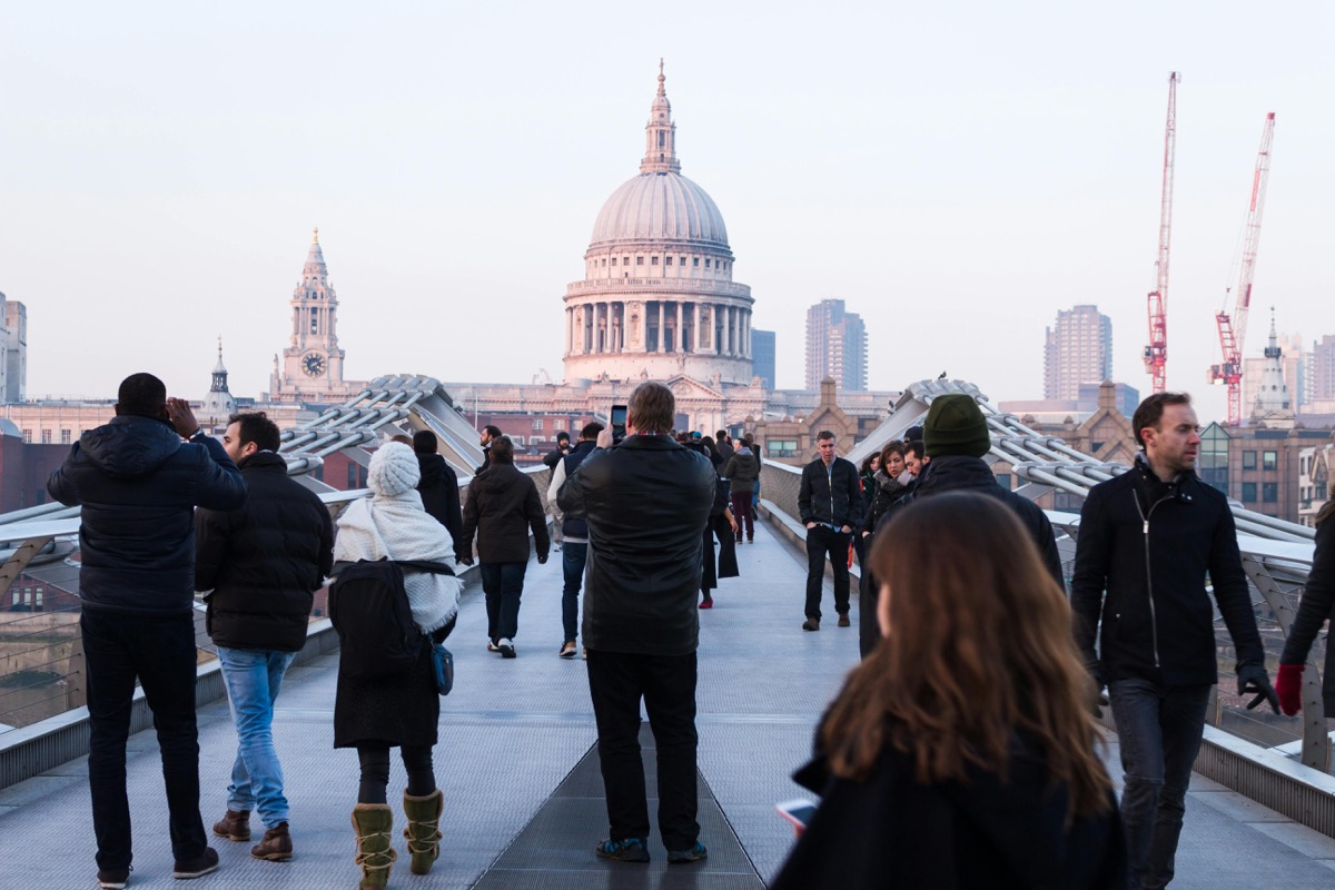 Millennium Bridge crowded with tourists walking towards St Pauls Cathedral London - before AI removal